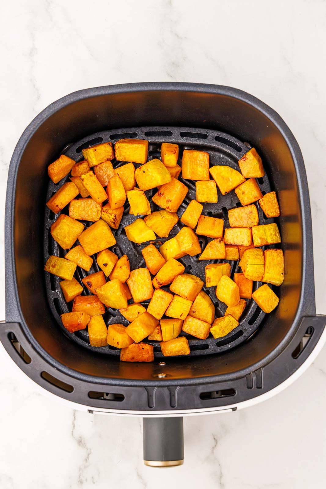 overhead view of black air fryer containing air fried butternut squash