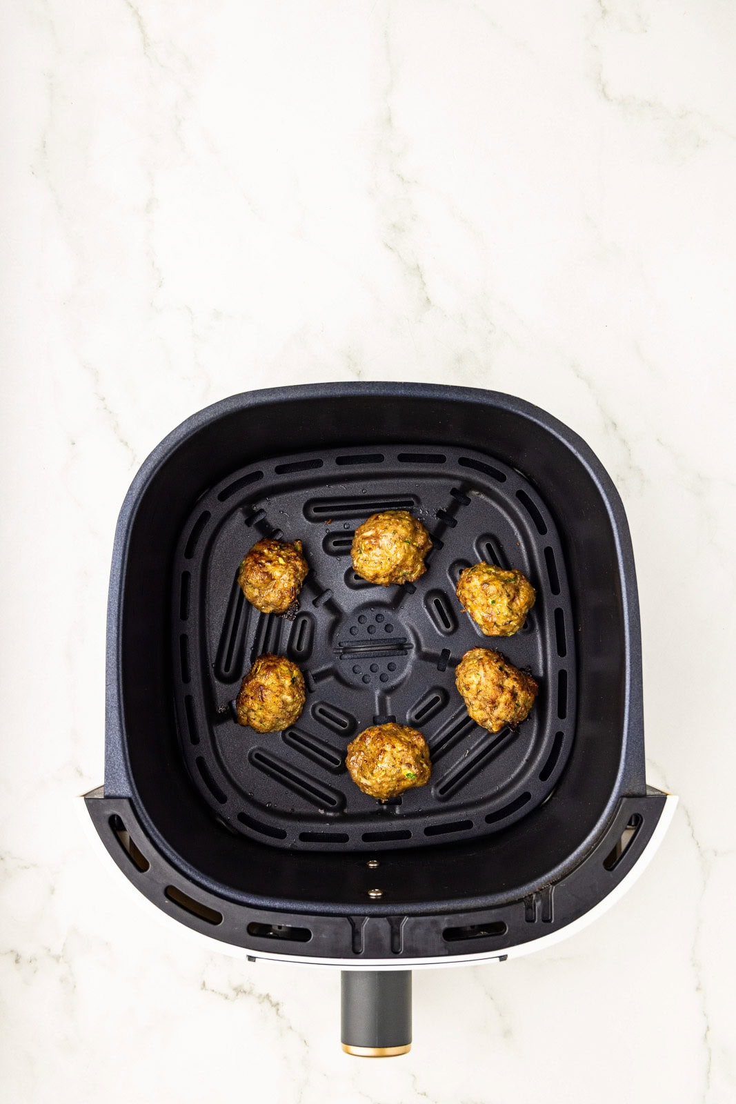 overhead view of black air fryer containing 6 air fried meatballs