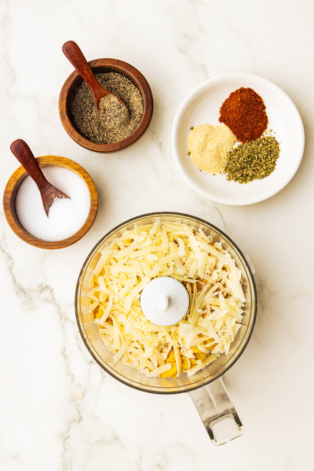 food processor with panko bread crumbs surrounded by bowls of seasoning and salt and pepper
