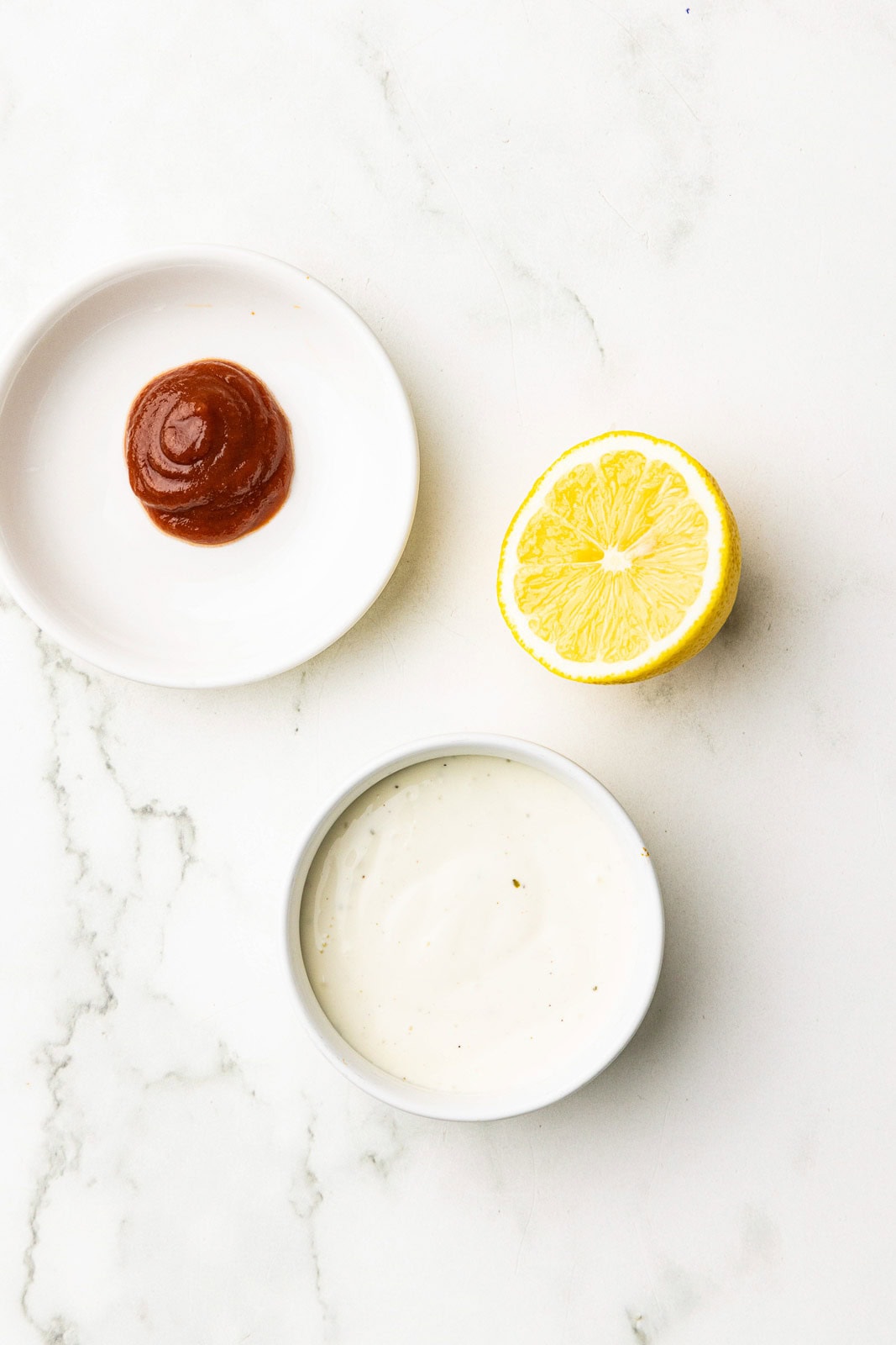 bowls of Sriracha, ranch dressing and lemon half