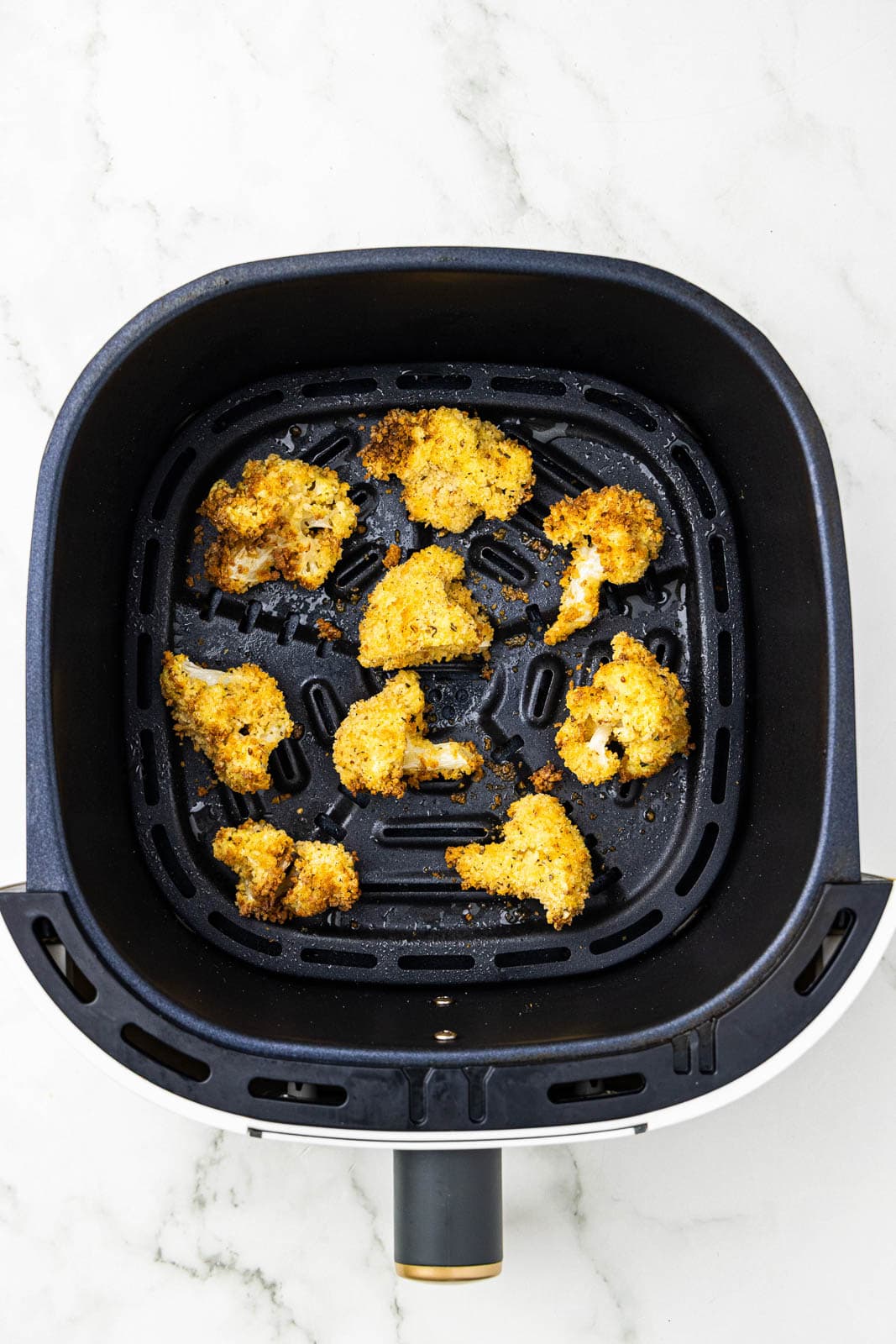 overhead view of black air fryer with air fried cauliflower florets
