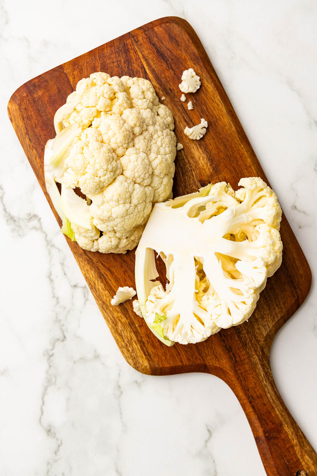 wooden cutting board of halved cauliflower head