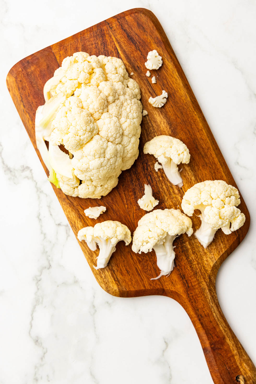 wooden cutting board of cauliflower and florets