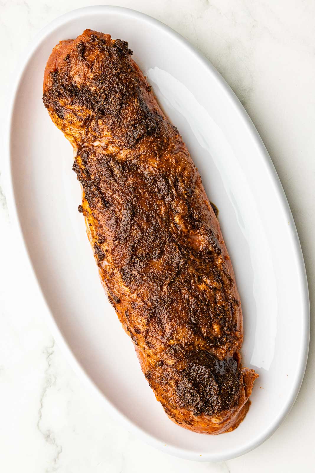 white platter with seasoning mixture on top of tenderloin