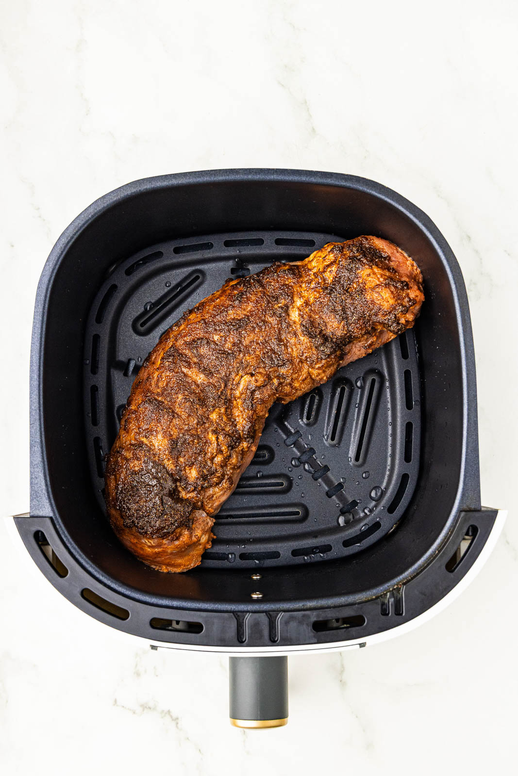 overhead view of black air fryer with pork tenderloin