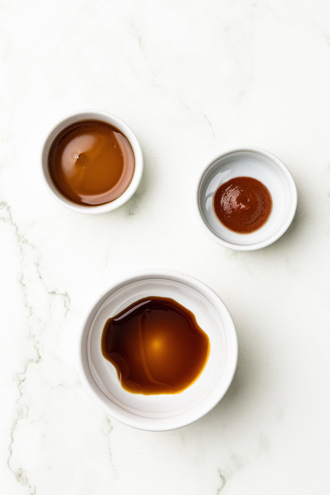 white bowls containing maple syrup, Sriracha and soy sauce