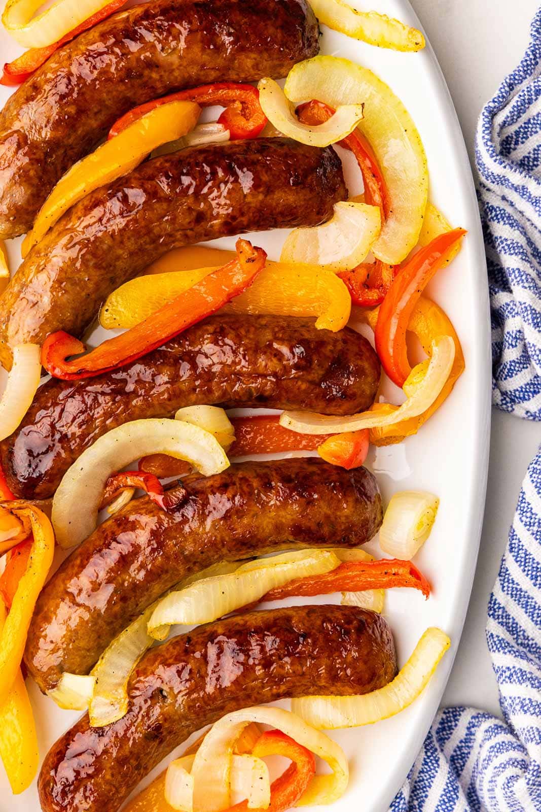 closeup of air fried sausage, peppers and onions on white platter