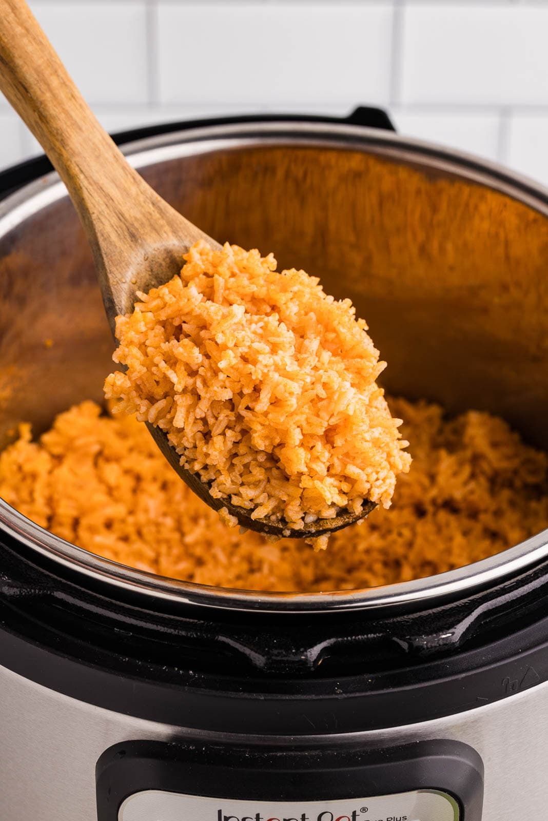 side view of instant pot containing Spanish rice with wooden spoon hold rice