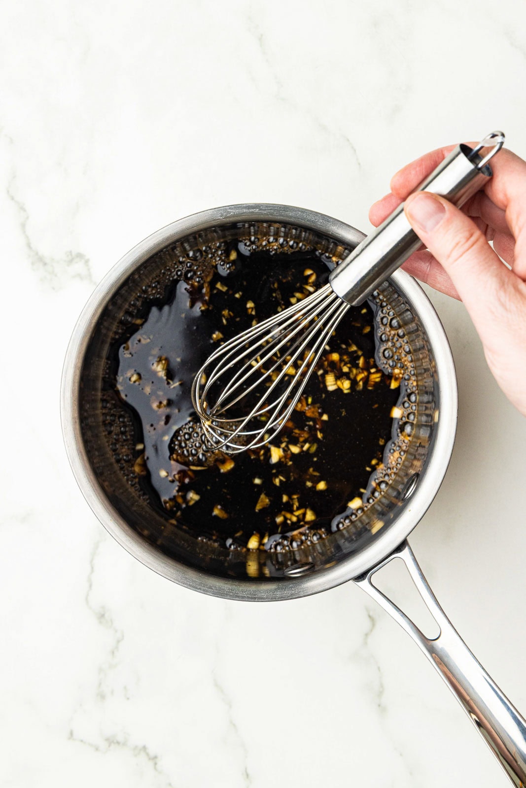 hand whisking mixture of all ingredients (except slurry) in saucepan