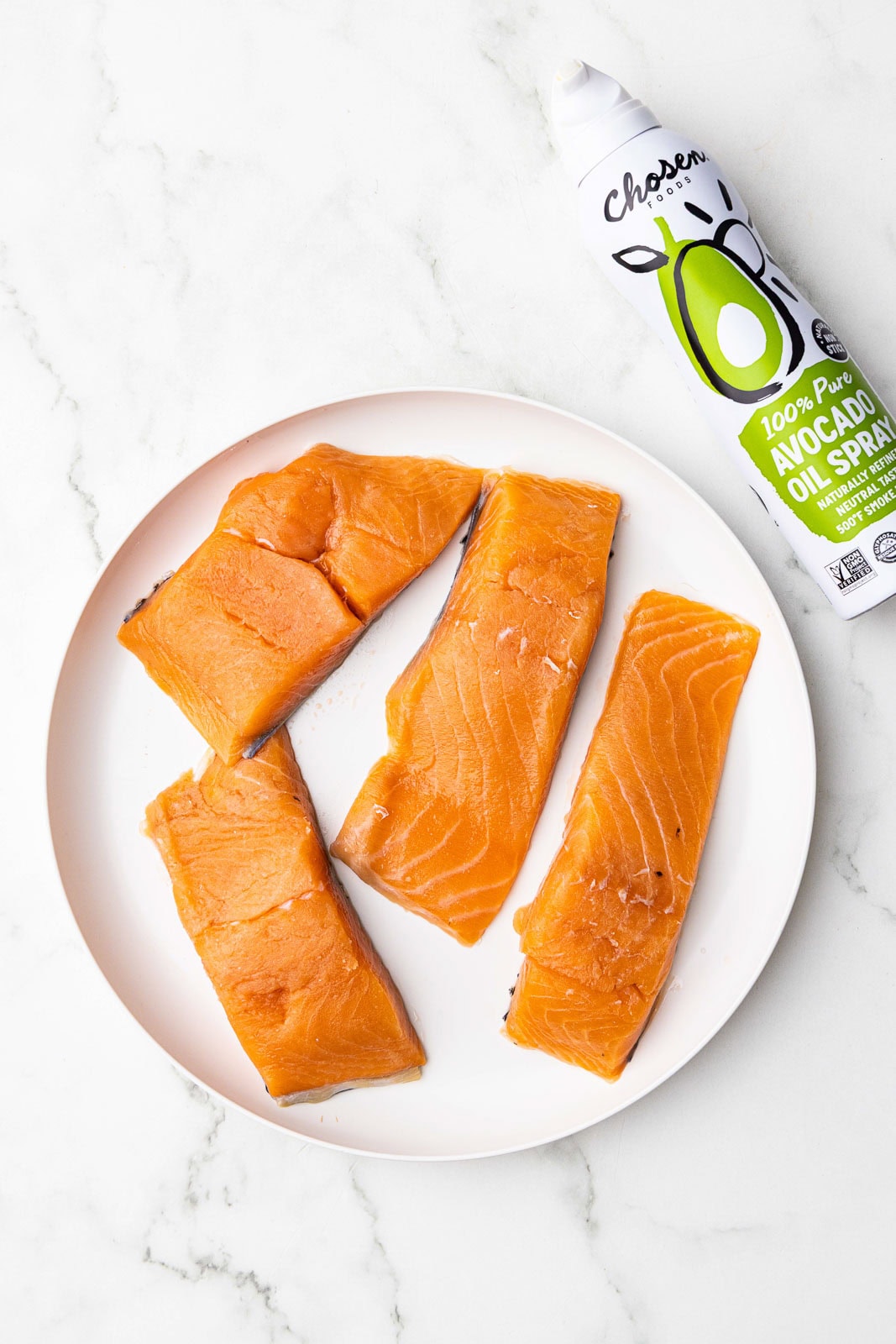 white dinner plate with dried salmon fillets and can of avocado spray on side