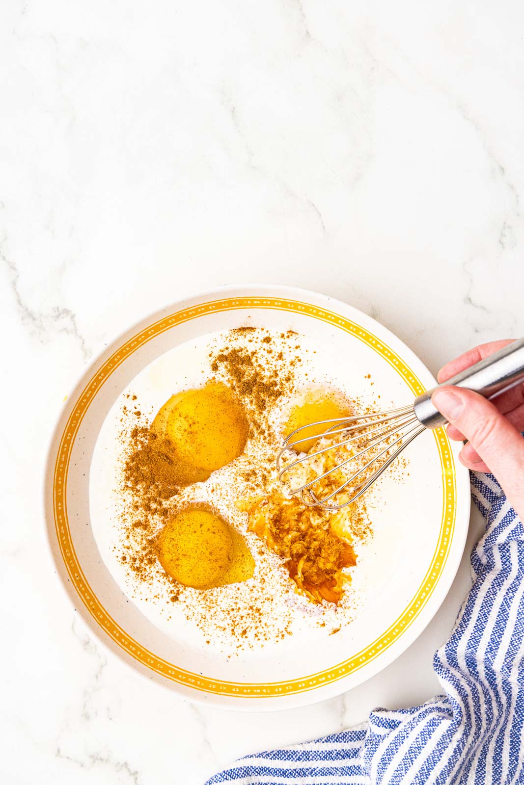 overhead view of shallow bowl of all ingredients with hand whisking ingredients