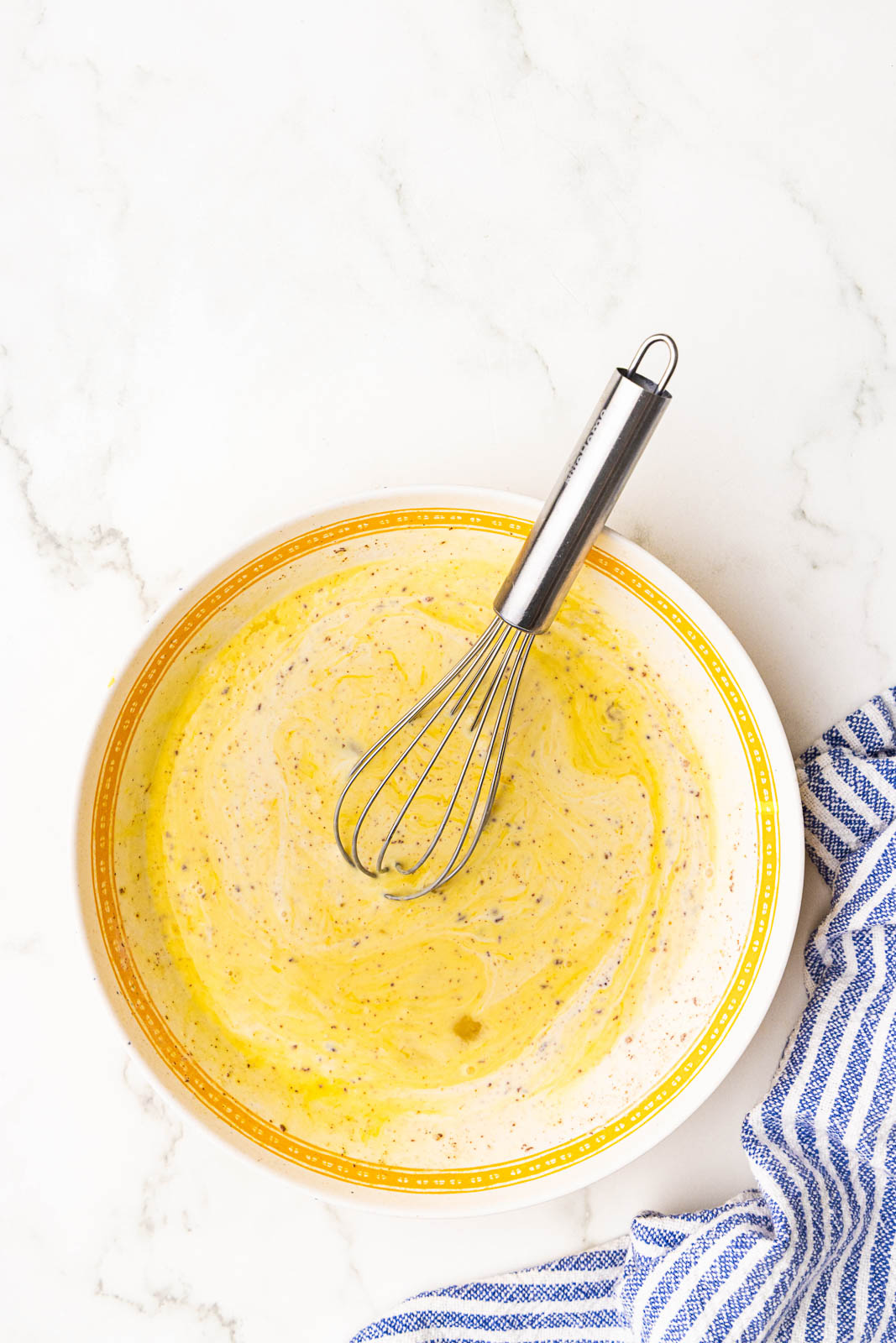 shallow bowl with all ingredients mixed with whisk inserted