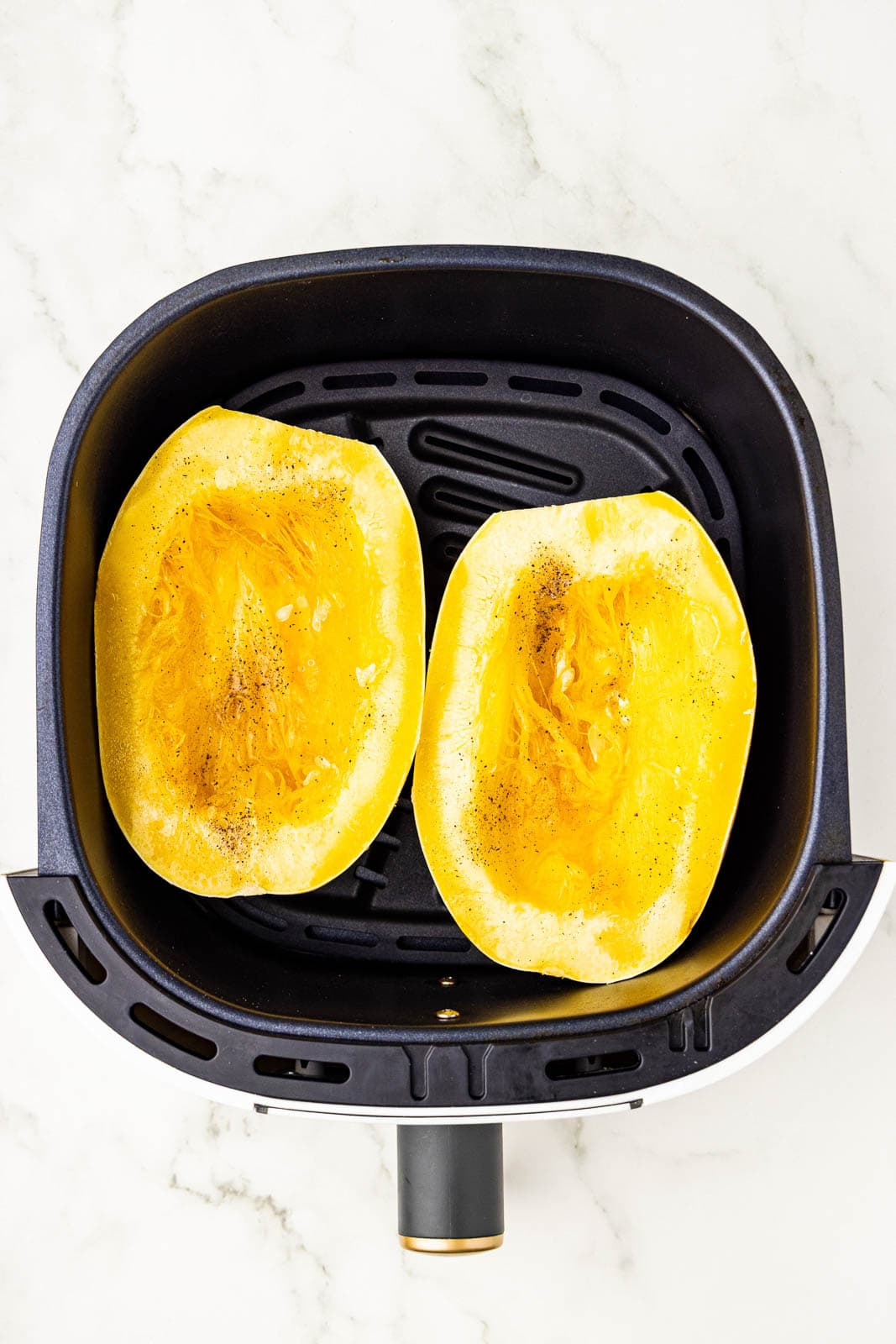 two seasoned and oiled squash halves in air fryer