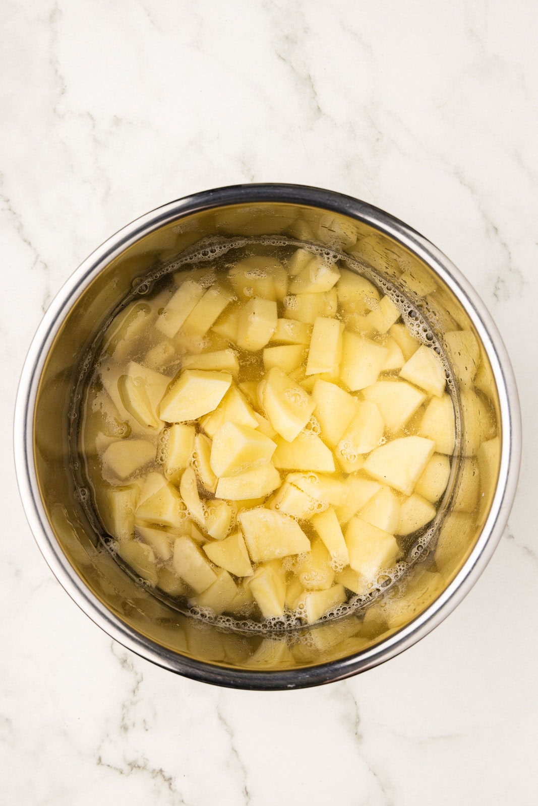 overhead view of cubed potatoes in instant pot container with water
