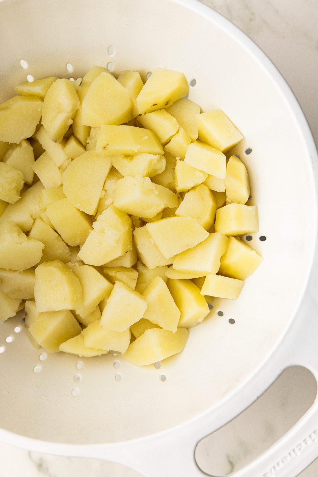 overhead view of cooked potatoes being drained in collander