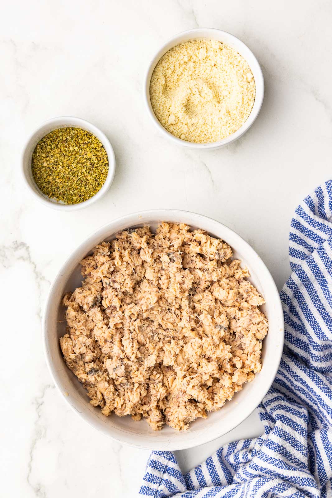 large bowl of canned salmon with bowls of seasoning and almond flour