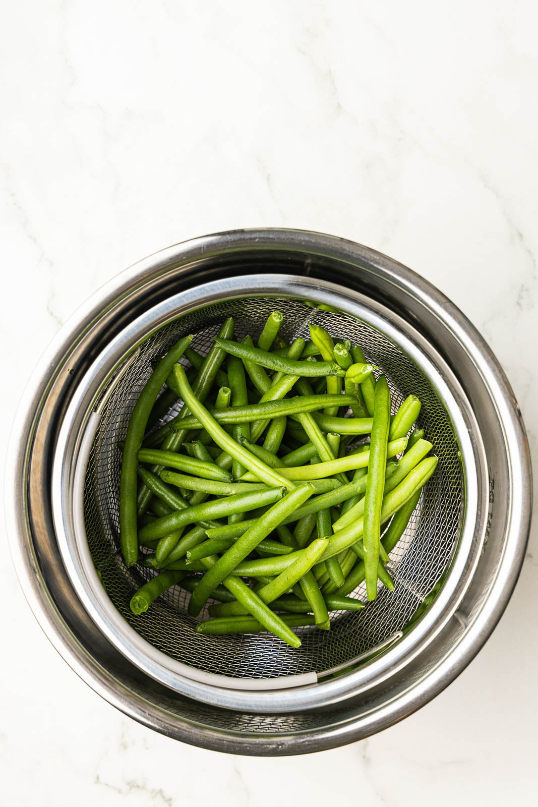 overhead view of instant pot with steamer basket filled with fresh green beans