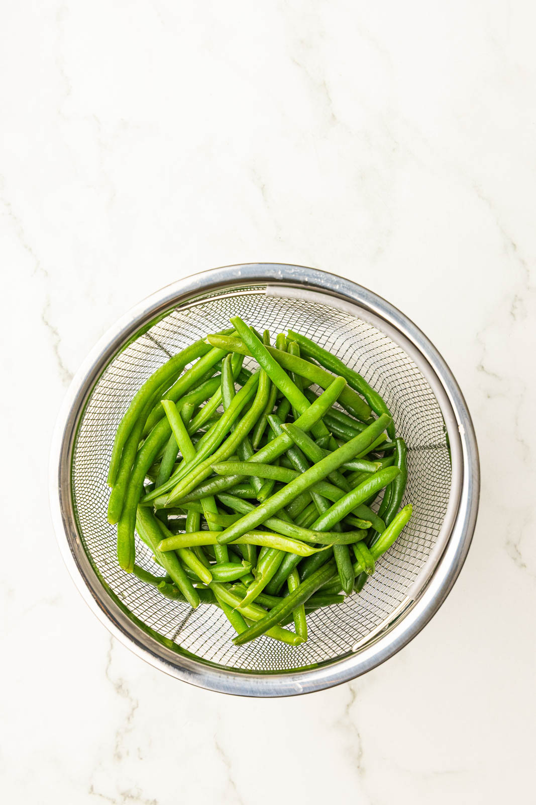 overhead view of steamer basket with cooked green beans