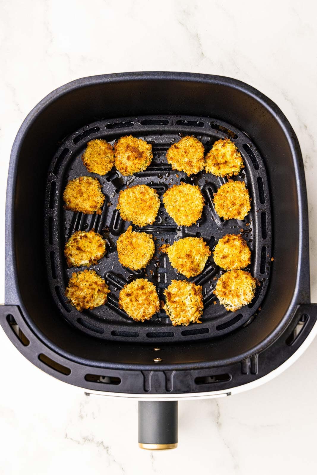 overhead view air fryer with air fried dill pickle chips