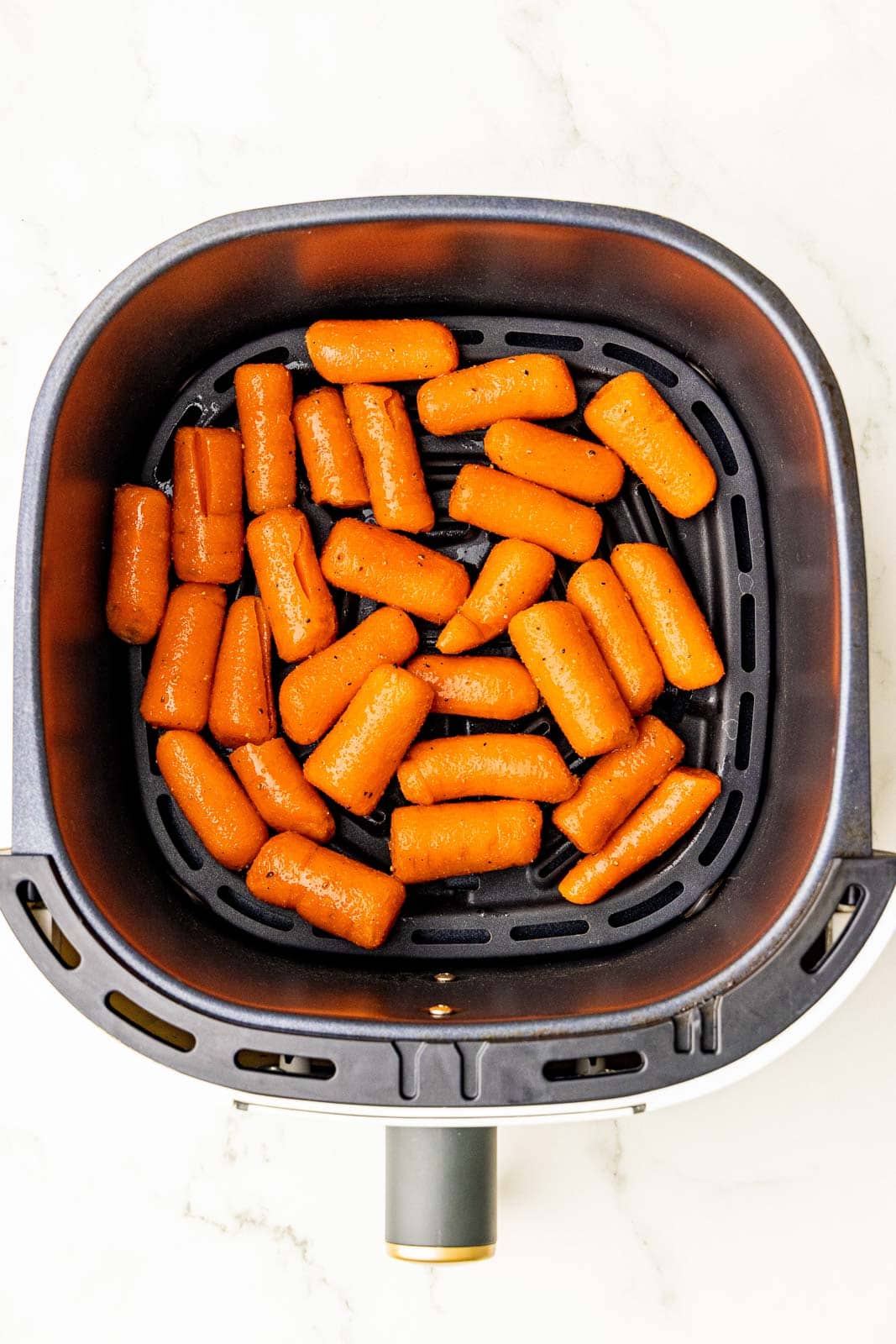 overhead view of air fryer containing seasoned baby carrots