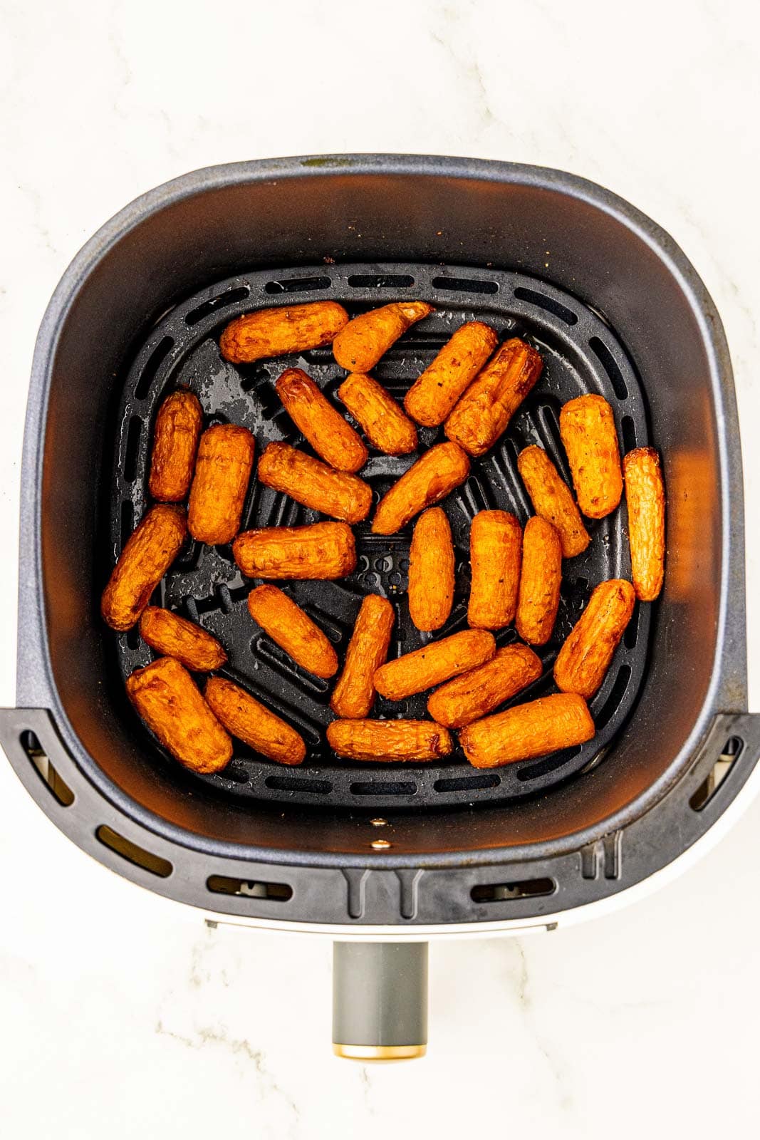 overhead view of air fryer with air fried baby carrots