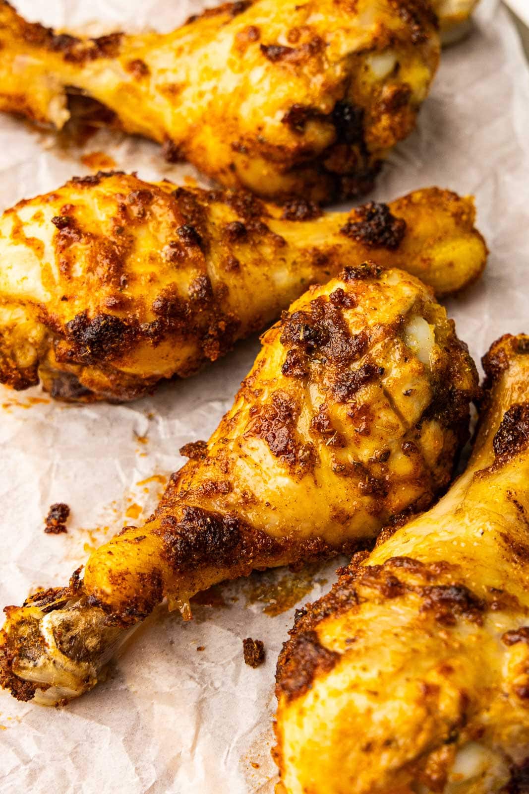 closeup view of four chicken drumsticks on parchment paper