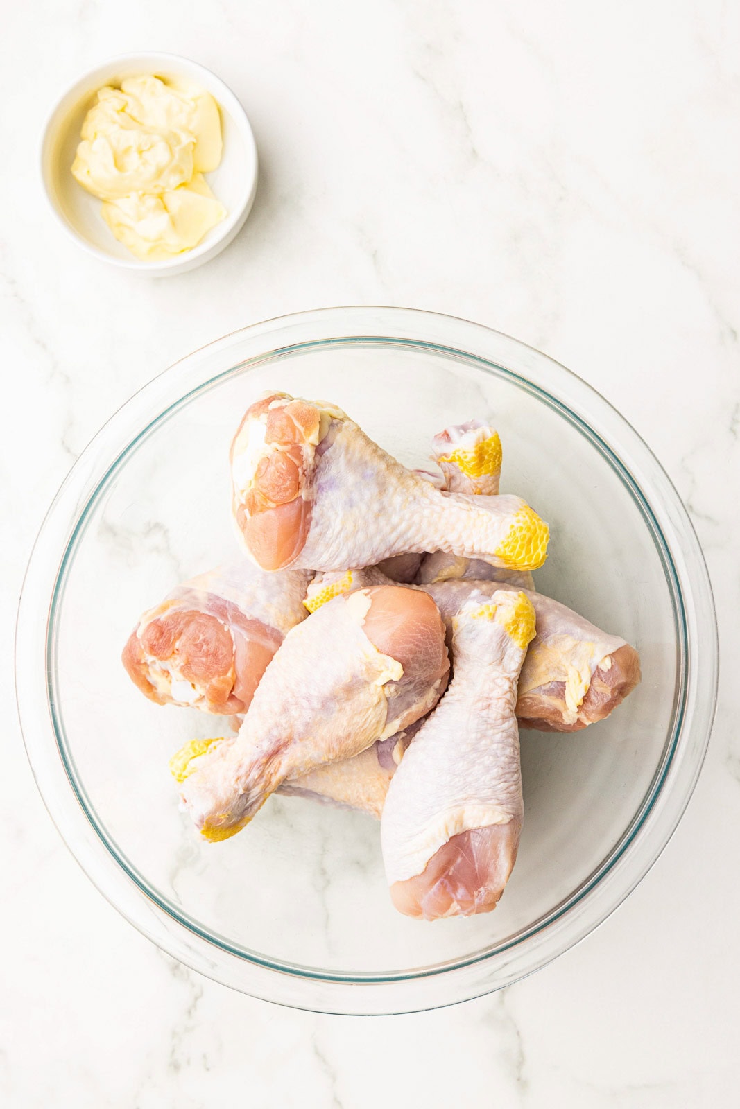 glass bowl of chicken drumsticks with small bowl of mayonnaise on side