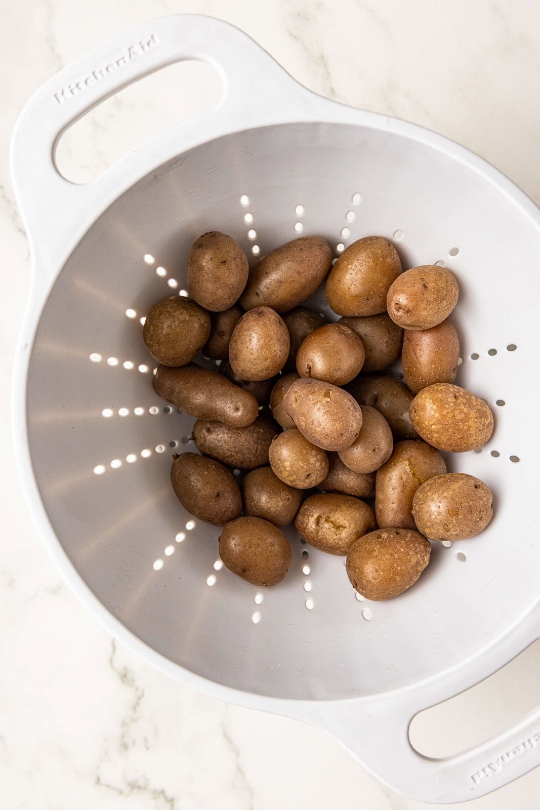 white colander with cooked potatoes