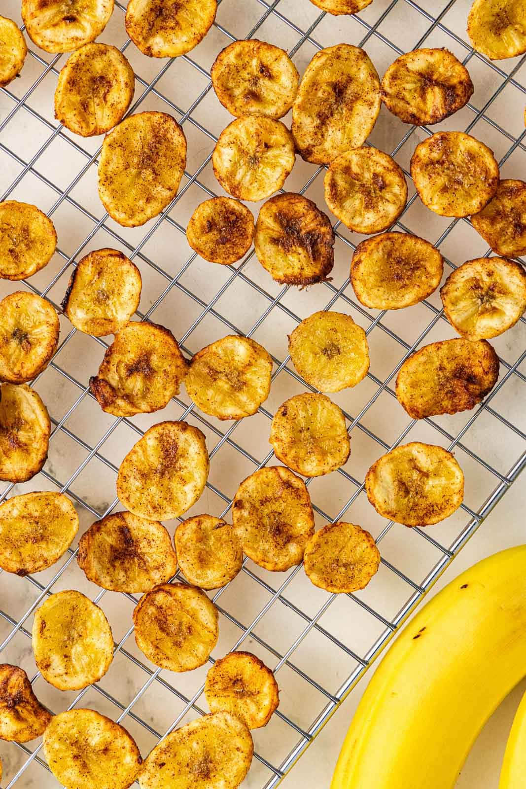 overhead view of air fried bananas on a cooling rack with whole bananas on side
