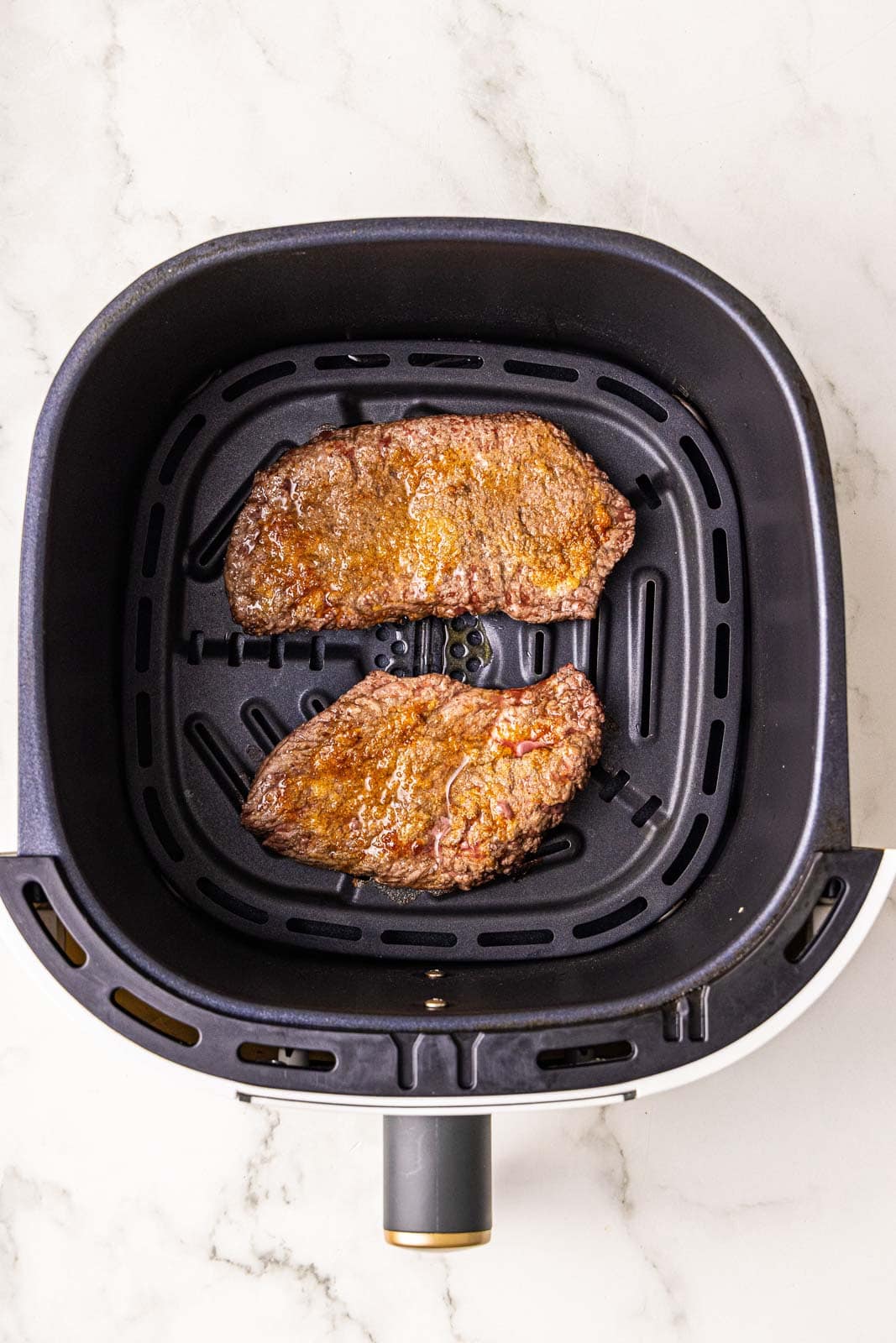 black air fryer with 2 air fried cube steaks