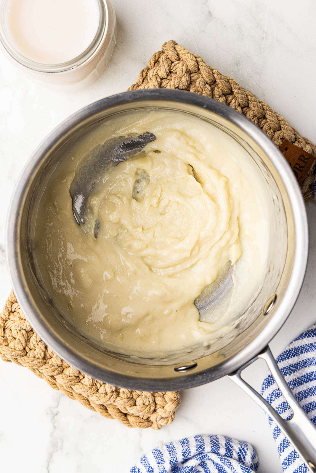 overhead view of sauce pan with flour and butter mixed with almond milk on the side