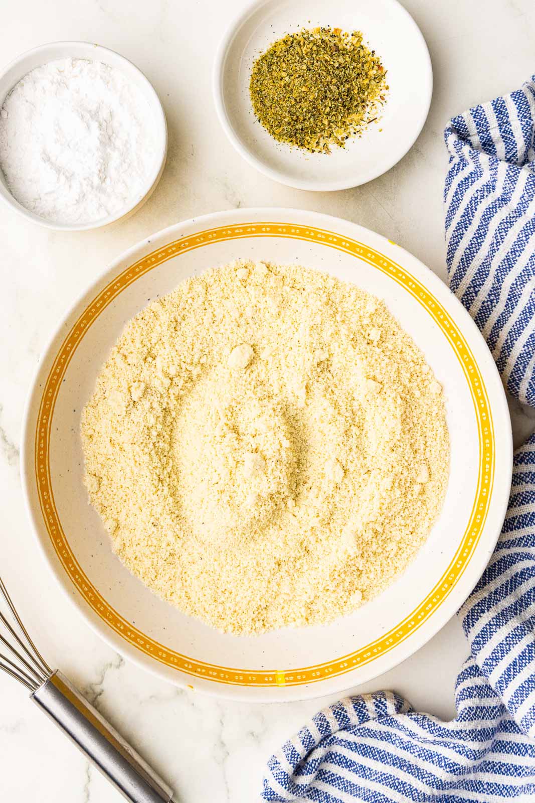 overhead view of large platter with almond flour, with bowls of tapioca flour, seasoning and whisk on the side
