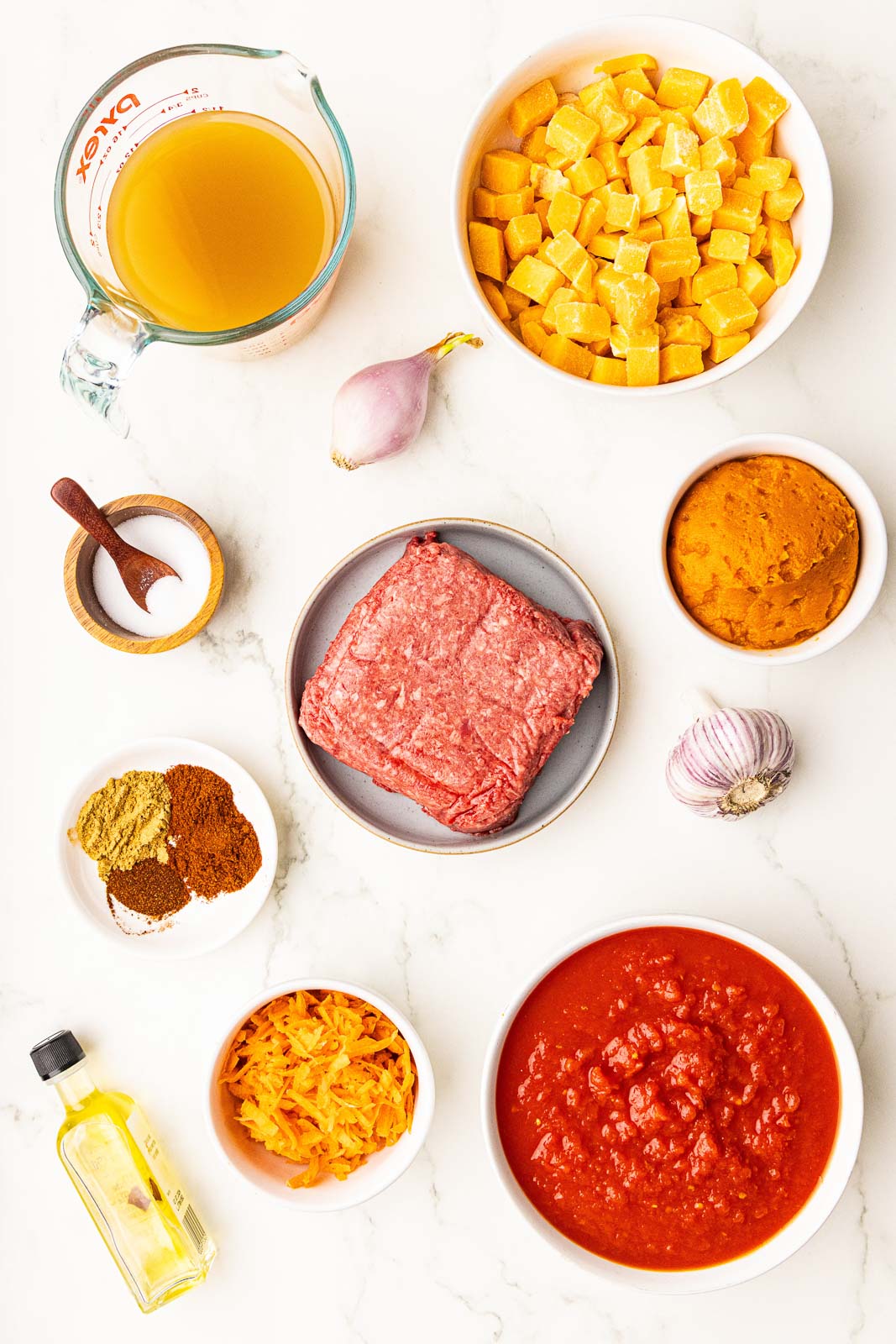 ingredients to include containers of ground bison, finely diced carrots, garlic, shallot, crushed tomatoes, canned pumpkin, butternut squash, bone broth, oil, salt and one dish with ancho chili and chipotle chili powders and cumin