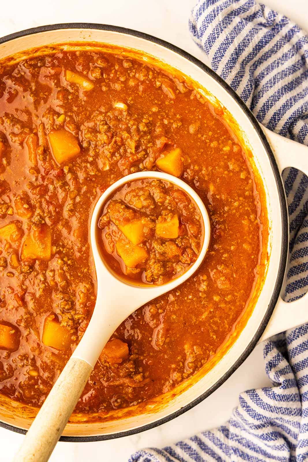 closeup of Dutch oven of chili with white ladle inserted