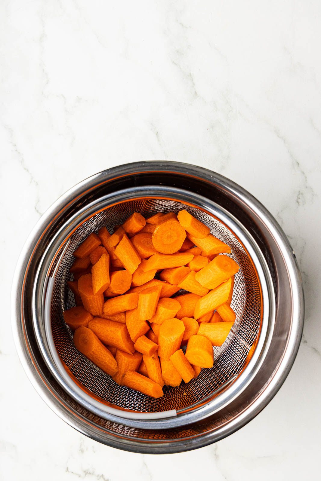 overhead view of wedged carrots in basket of instant pot