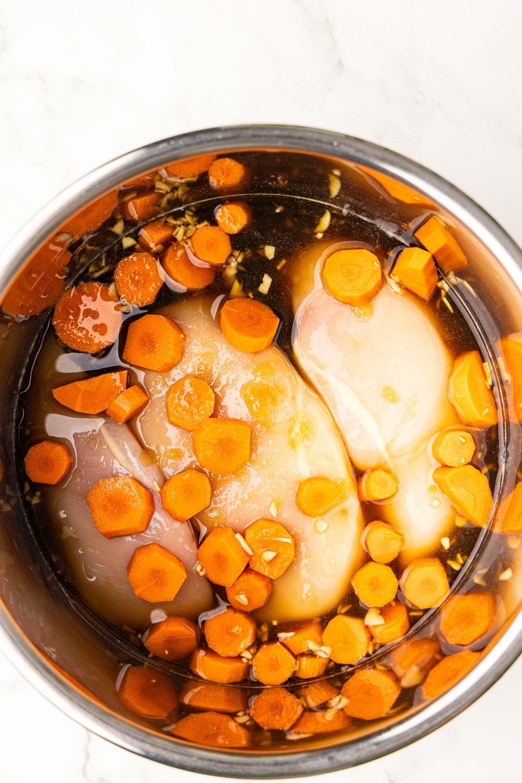 instant pot bowl with chicken, carrots water and marinade
