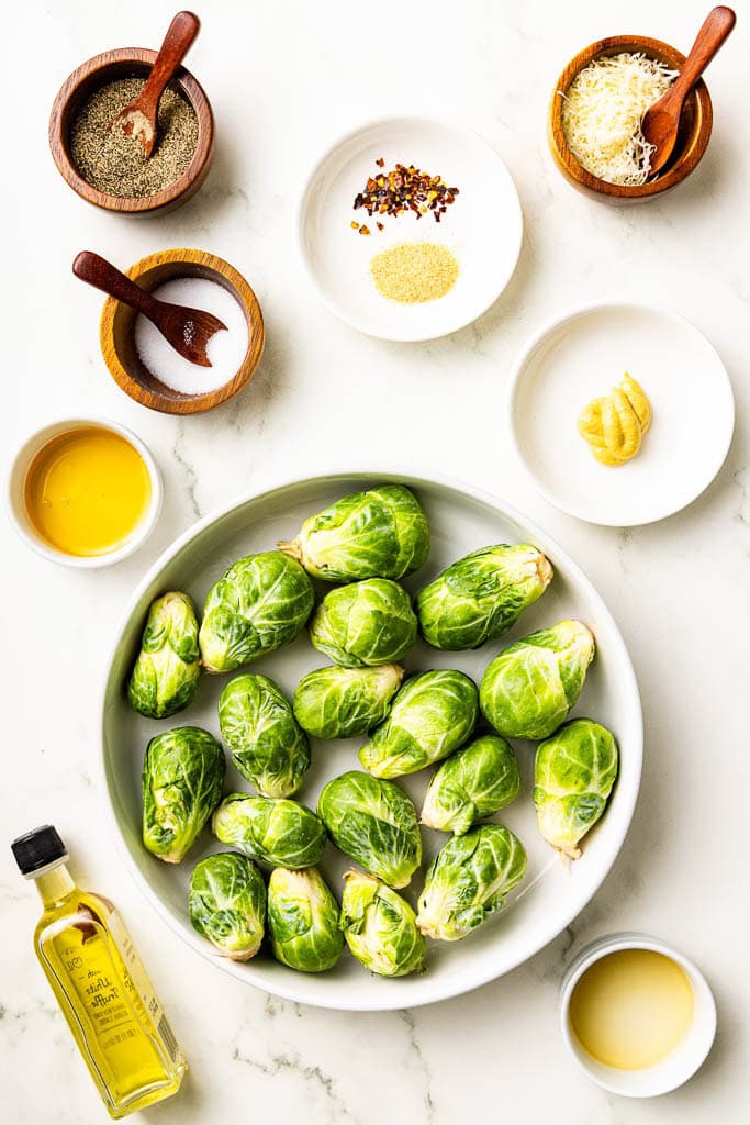 ingredients to include containers of Brussels sprouts, salt, pepper, red pepper flakes and garlic powder, honey, Dijon mustard, apple cider vinegar, Parmesan cheese and olive oil