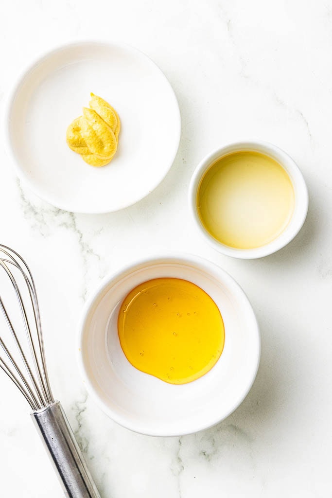 3 white bowls containing Dijon mustard, apple cider vinegar and honey