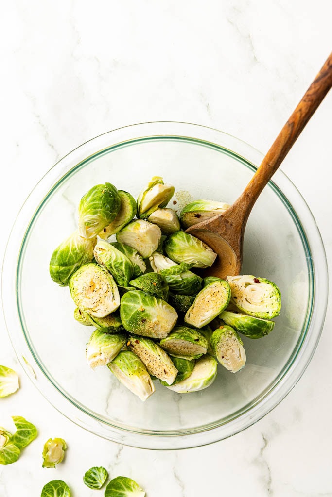 glass bowl of Brussels sprouts with wooden spoon