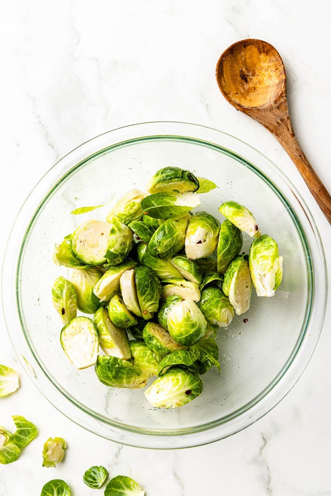 glass bowl of Brussels Sprouts with wooden spoon on side