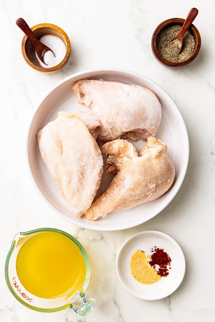 ingredients to include containers of frozen chicken breasts, surrounded by salt, pepper, garlic pepper and paprika and chicken broth