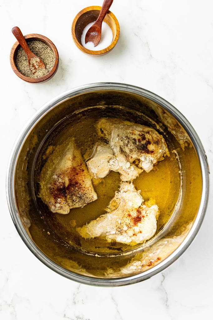 cooked seasoned chicken breasts in chicken broth with salt and pepper in background