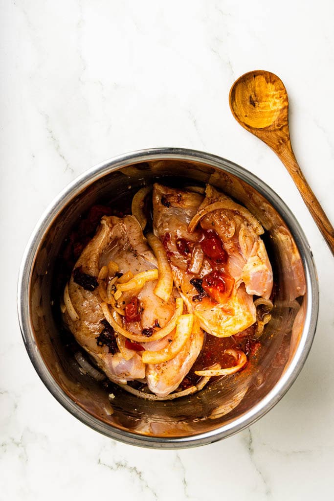 instant pot with cooked chicken and veggies with wooden spoon on side
