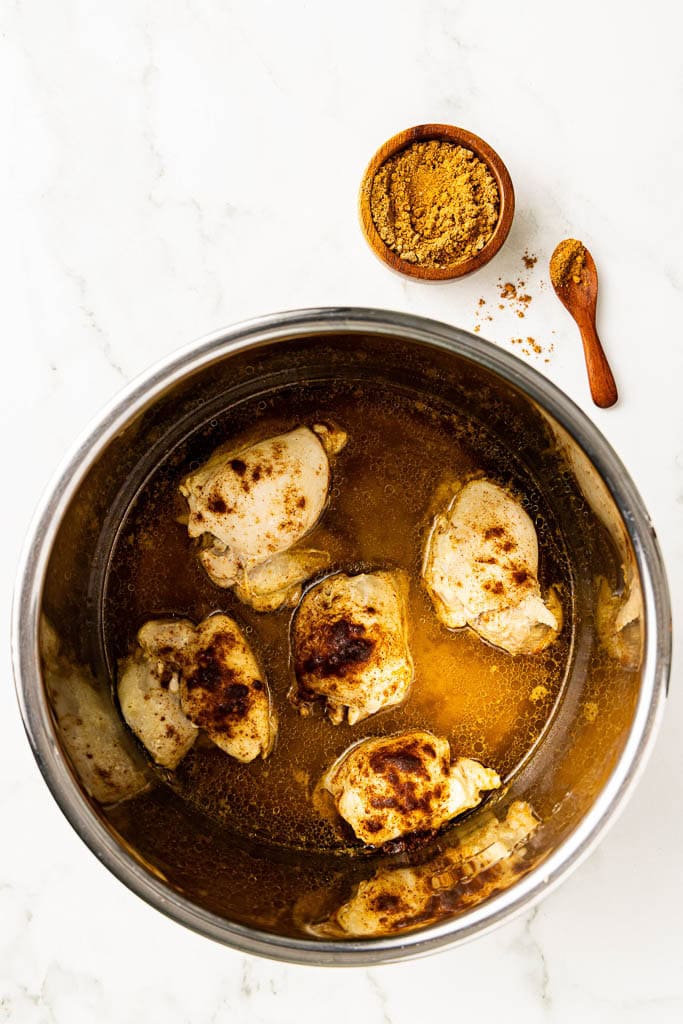 instant pot with cooked chicken thighs with container of taco seasoning on side