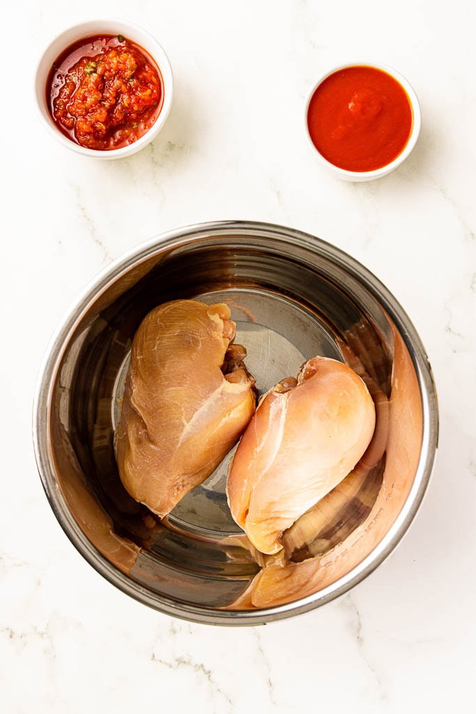 instant pot with 2 chicken breasts with salsa and tomato sauce on side