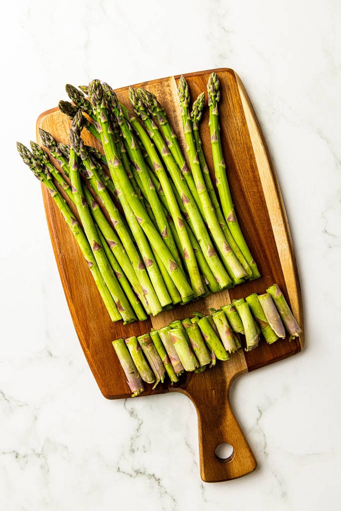 wooden cutting board with asparagus with ends cut off