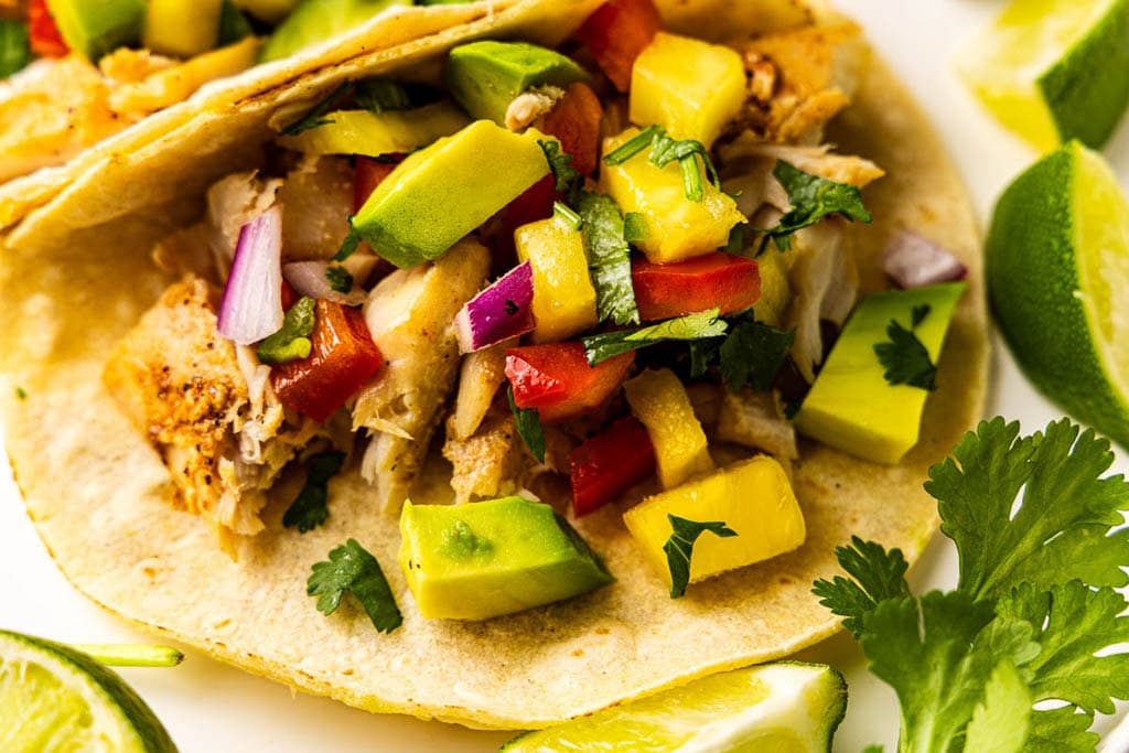 closeup of filled tortillas with lime wedges and cilantro