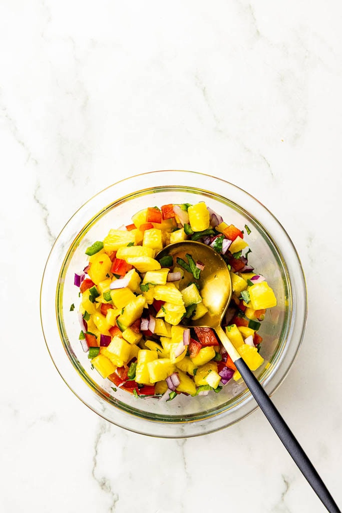 glass bowl with pineapple salsa and spoon